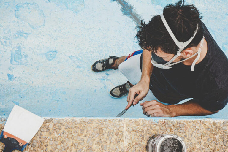 Un homme travaillant sur le remplacement du liner piscine desjoyaux dans une piscine vide.