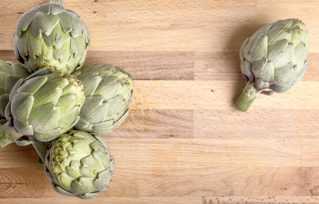 Des artichauts sur une planche à découpe en bois
