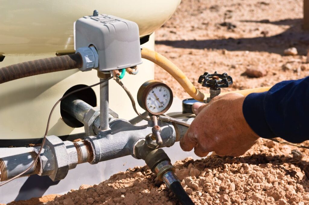 Un homme faisant un branchement de surpresseur sur une cuve de 1000 L