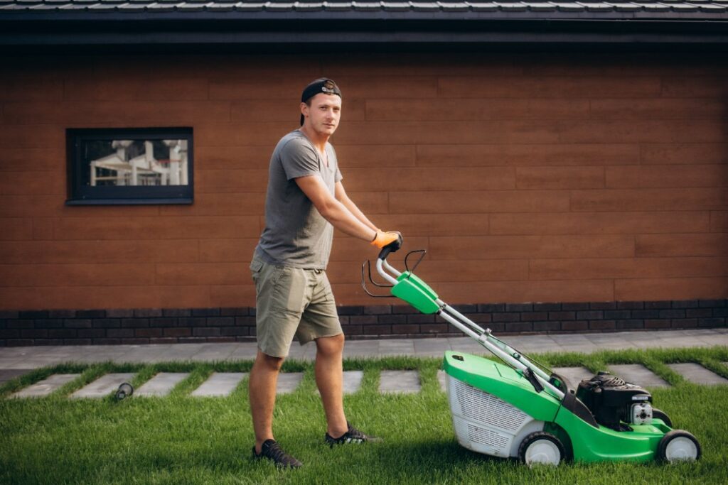 Un homme qui tond la pelouse avec une tondeuse