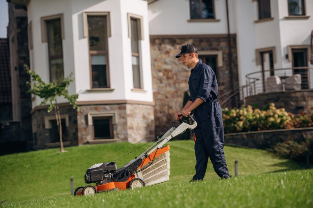 Un jardinier qui tond la pelouse devant une maison