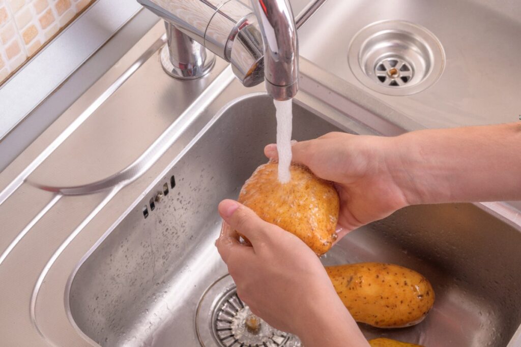 Une personne qui lave une pomme de terre