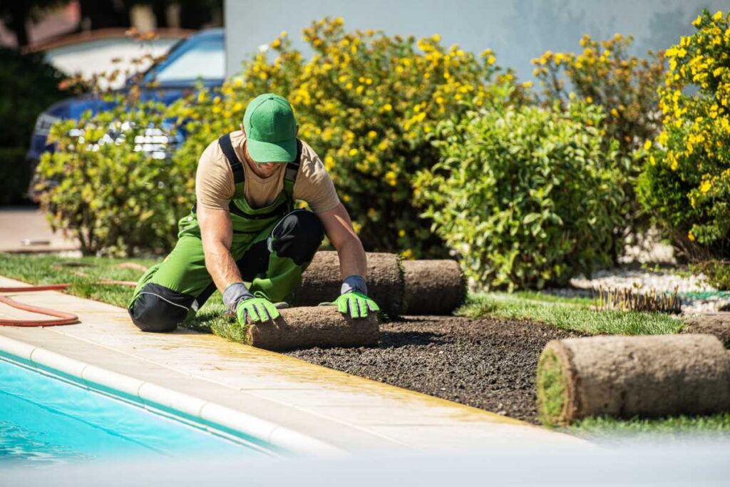 Un paysagiste posant du gazon près d'une piscine