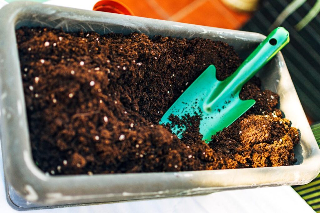 Une pelle verte à moitié enterrée dans la terre de compost
