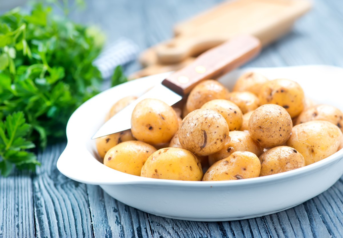 Un bol rempli de pommes de terre fraîches avec un couteau