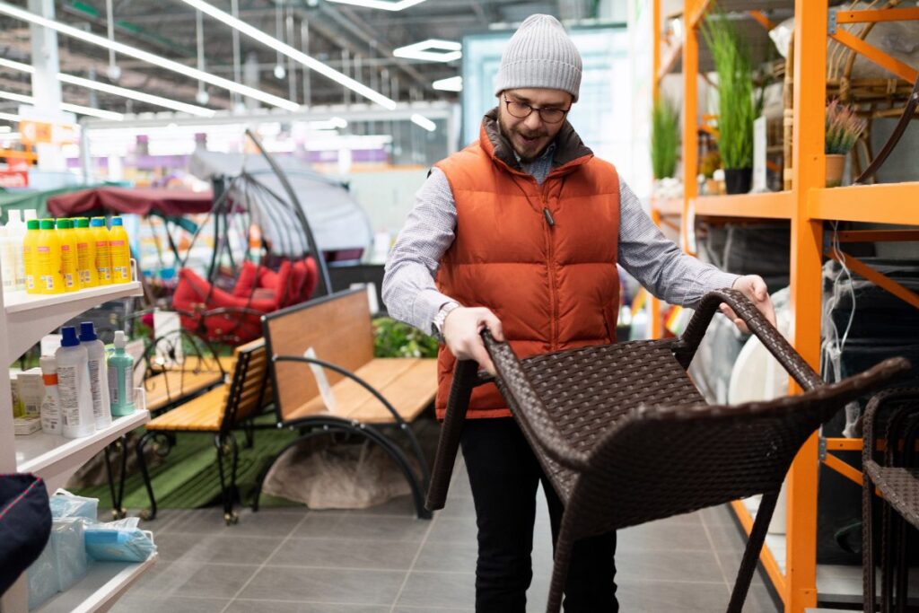 Un homme qui tient et regarde une chaise dans un magasin