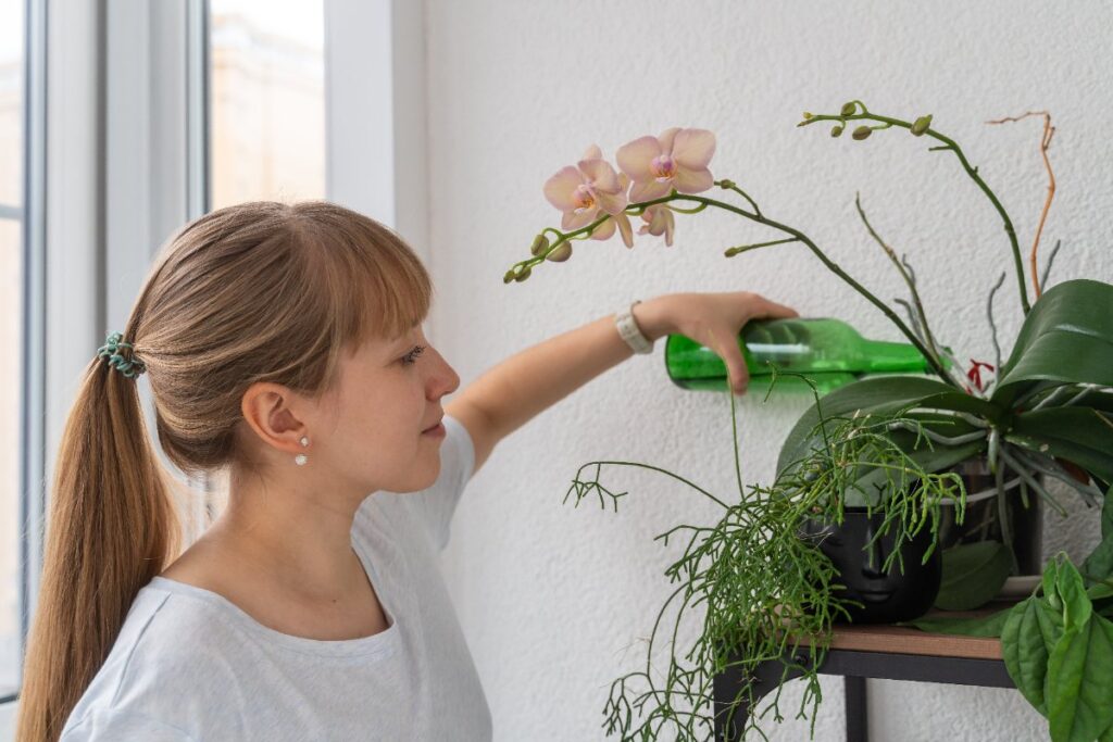 Une jeune femme arrosant des orchidées